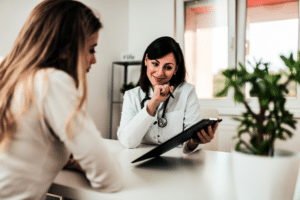 A female doctor discusses LASIK costs with a patient in a clinical setting.