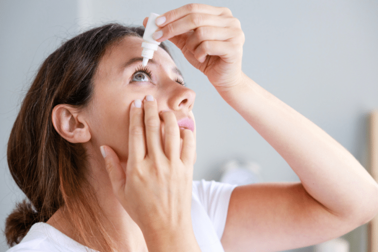 A woman applying eye drops to her eyes, following a key step in LASIK recovery tips for optimal healing.