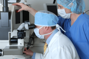 A doctor in a blue hat examining a patient’s eyes, representing LASIK lifestyle benefits.