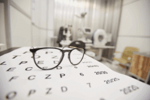 A pair of glasses on a table in an eye clinic, illustrating the importance of details about LASIK timing for patients.