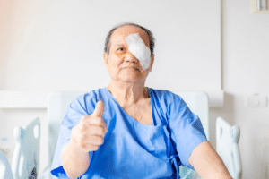 An elderly man with a bandaged eye, representing cataract surgery recovery tips.