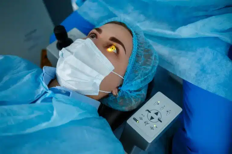 A woman in a blue surgical gown and mask rests on a medical bed, suggesting she is a candidate for LASIK evaluation.