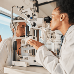 A woman interacts with an eye exam machine, highlighting the importance of primary eye care for vision assessment.